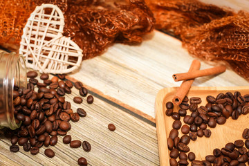 scarf, glass jar, cookies, cinnamon sticks and scattered coffee beans on vintage wooden table. Top view. Coffee break.