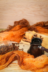 ceramic turk, scarf, glass jar, cookies, cinnamon sticks and scattered coffee beans on vintage wooden table. Top view