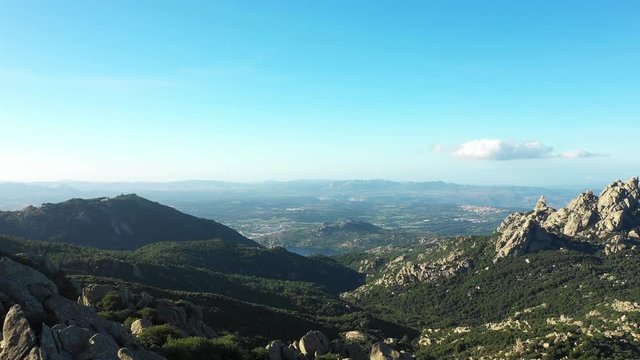 Video from above, aerial view of a beautiful valley surrounded by granite mountains and green vegetation, Monte Limbara, Sardinia, Italy.