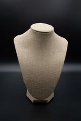 Empty tan jewelry stand bust isolated on black background.