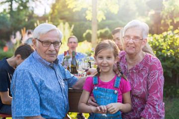 during a family bbq grandparents pose with their granddaughter 
