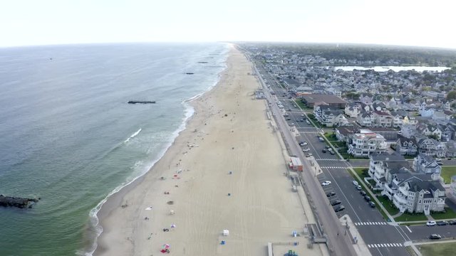 Aerial drone shot over the sandy beaches and green ocean waves along the coast of Belmar, New Jersey.