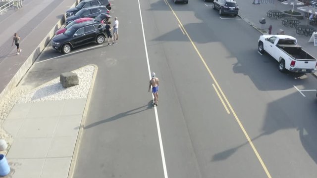 Aerial drone shot above a road with a skateboarder and vacationers on the street off the coast of Belmar, New Jersey.