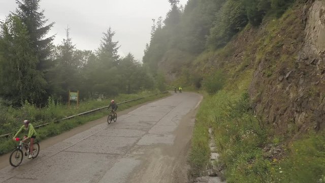 Aerial view of a couple bikers peddling on a misty road in Colbita, Romania during Tura Cu Copaci bike race