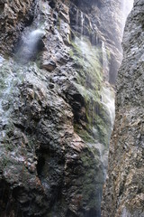 Waterfall shooting out between mountain faces in canyon at Höllentalklamm in German Alps
