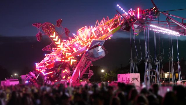 Crowds Have Fun On Bright Carnival Rides At Night