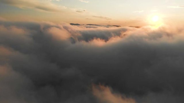 Flying through the clouds at dusk or dawn. Flying in pink clouds in the sun. Aerial view. North Caucasus
