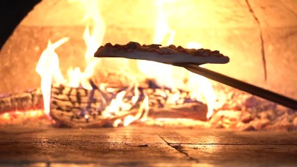 Slow Motion toasting the bottom crust of pizza while cooking in wood fired oven