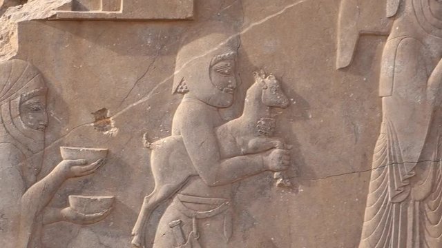 Bas-relief of people with offerings in ancien Persepolis. Shiraz, Iran.