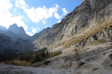 Mountain valley with dry river bed and trees in autumn sun at Höllental in German Alps