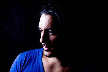 Moody portrait of man with black hair and blue t shirt