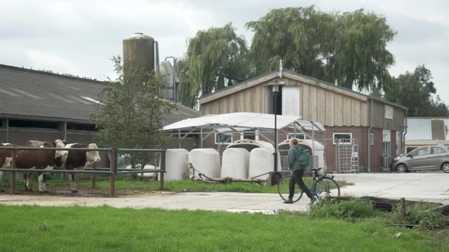 Women entering or arriving to organic farm by bicycle green farm and enery free factory industrial