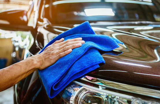 Car care service worker used microfiber cloth cleaning outside car 