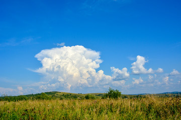 Landscape with beautiful large white clouds in the blue sky on a sunny day