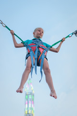 Girl hanging on rubber straps on the background of a glowing tower. The invigorating ride.