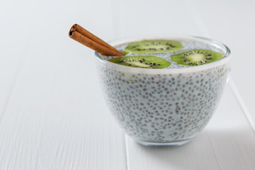 Cinnamon sticks and a glass bowl of Chia seeds with milk on the white table.