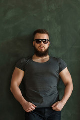 Obraz premium Bodybuilder in sunglasses portrait. Muscular man with a beard in a tight t-shirt. Stylish and sporty.