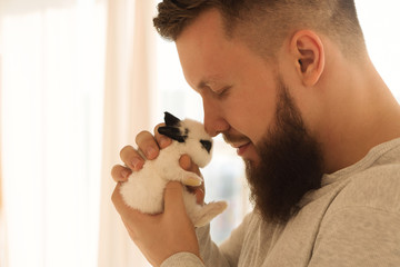 Bodybuilder with a little rabbit. Muscular man with a beard in a tight T-shirt holding a pet....