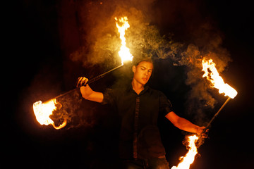 Fire show. Fire dancer dances with two Staff. Night performance. Dramatic portrait. Fire and smoke....