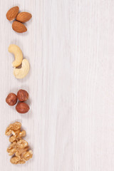Fototapeta na wymiar Different nuts and almonds as source vitamins and minerals, copy space for text on white board