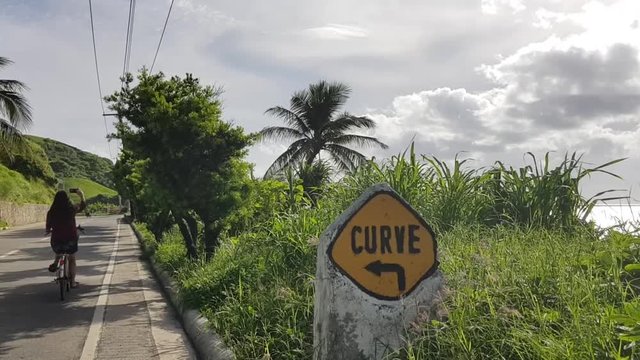 Yellow curve sign beside a road and thick grass in Batanes, Philippines