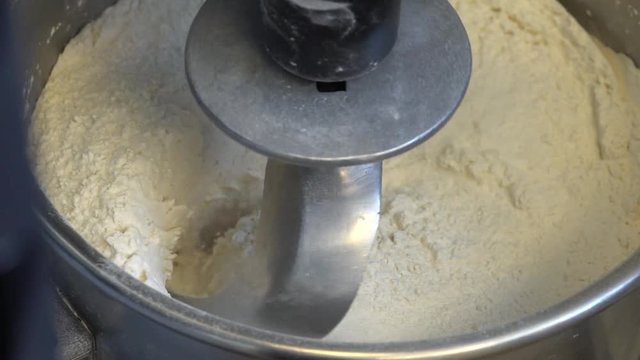 Slow motion of flour for pizza dough mixing in power mixer