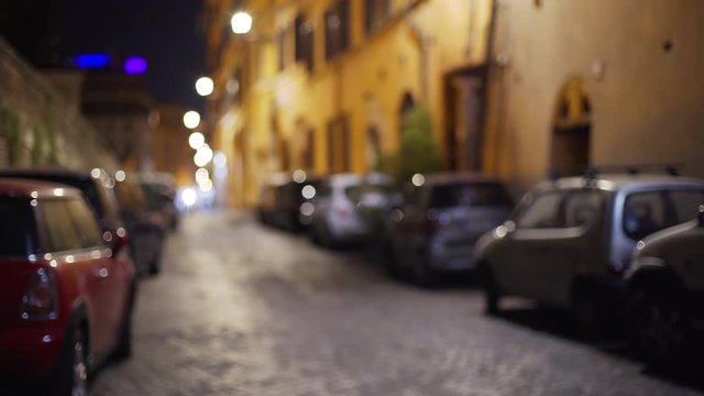Out of focus background of cars parallel parked on a small street in Rome Italy