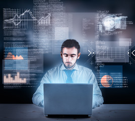 Businessman working on laptop with a futuristic infograph interface in front of him