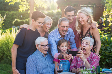  During a bbq, the family have fun sharing a video on a phone