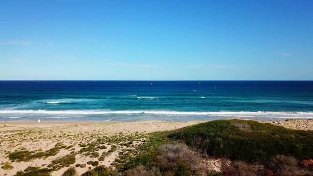 aerial dolly style into a white beach with kitesurfers