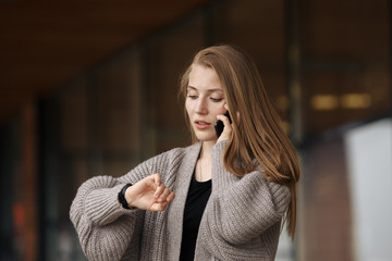 Youth and technology. Amazed young woman with smartwatch using mobile phone. Colorful studio portrait. Pink background.