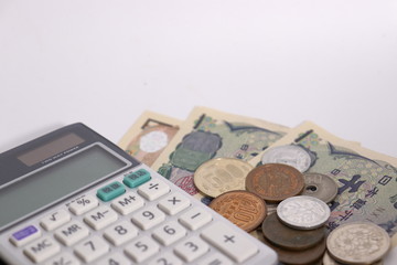 白背景に日本のお金(お札と小銭)と計算機