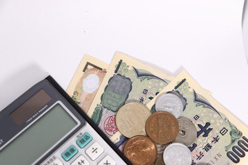 白背景に日本のお金(お札と小銭)と計算機