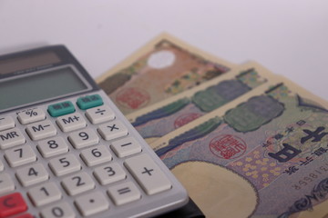 白背景に日本のお金(お札と計算機	