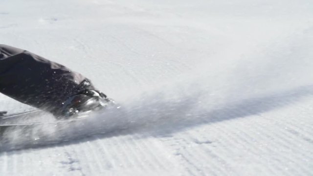 Close up slow motion skis turning on groomer