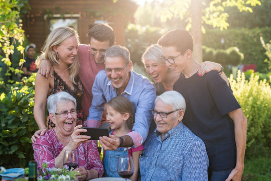During a bbq, the family have fun sharing a video on a phone
