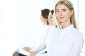 Attractive businesswoman at meeting or conference against the background of colleagues. Group of business people at work. Portrait of lawyer or secretary