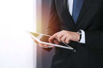 Unknown businessman holding digital tablet in office