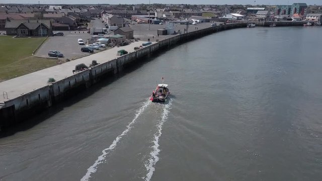 Aerial view of small fishing boat entering the harbour at Amble in Northumberland UK.