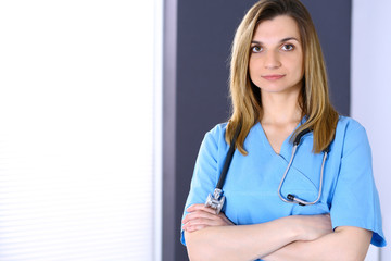 Woman doctor at work in hospital office. Portrait of female physician with arms crossed. Medicine and health care concept