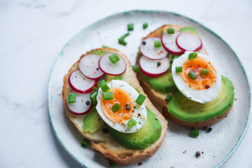 Healthy breakfast, Toasts with avocado, egg, radish, sweet onions, Diet food, On a light marble background, Selective focus closeup
