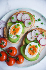 Healthy breakfast, Toasts with avocado, egg, radish, sweet onions and tomatoes, Diet food, On a light marble background, Selective focus closeup