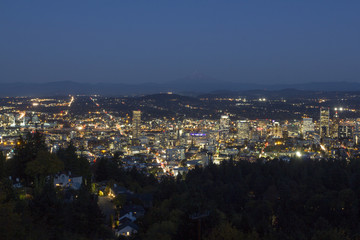 Portland Oregon downtown skyline at evening blue hour with Mt Hood in the distance.