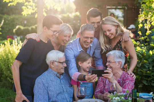  During A Bbq, The Family Have Fun Sharing A Video On A Phone