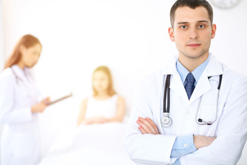 Medicine doctor standing and  smiling on the background with patient in the bed