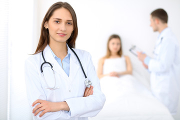 Fototapeta premium Medicine doctor standing and smiling on the background with patient in the bed