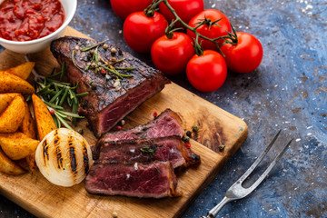 Delicious beef steak on wooden cutting board. Sliced grilled beef barbecue with cherry tomatoes