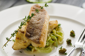 Fillet of halibut on a pillow of stewed leeks on the white plate.