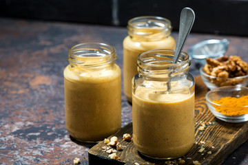 healthy carrot smoothies with turmeric and nuts on dark background