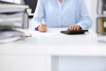 Unknown female bookkeeper or financial inspector calculating or checking balance, making report, close-up. Internal Revenue Service at work with financial document. Tax and audit concept